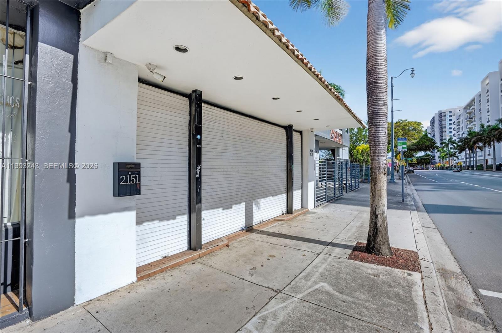 A commercial storefront with a white roll-down security gate and a street-side sidewalk — 2151 SW 8th St, Miami FL 33135, MIAMI, FL