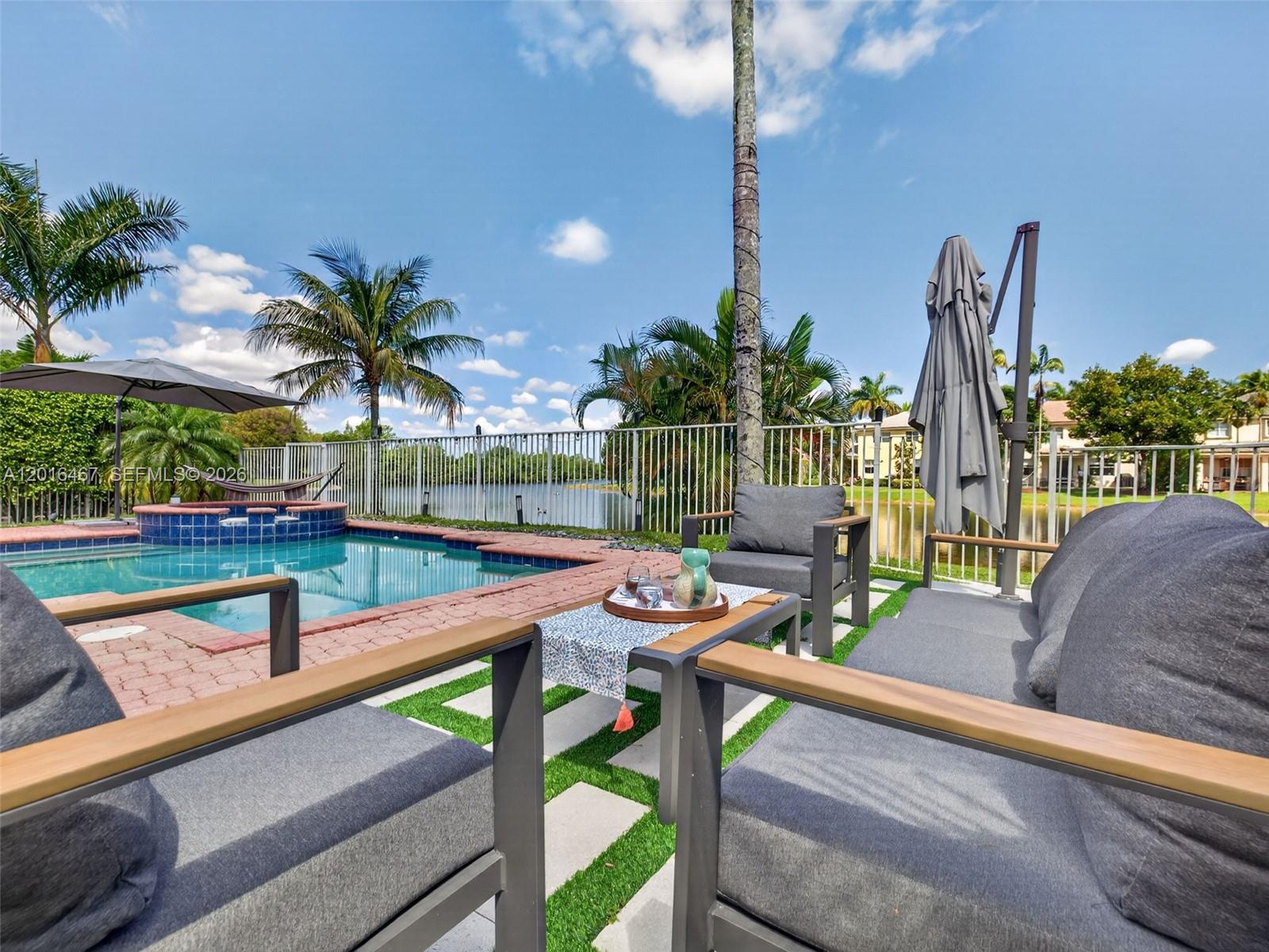 A patio features outdoor furniture, a swimming pool, and a view of a lake — 250 Conservation Dr, Weston FL 33327, WESTON, FL