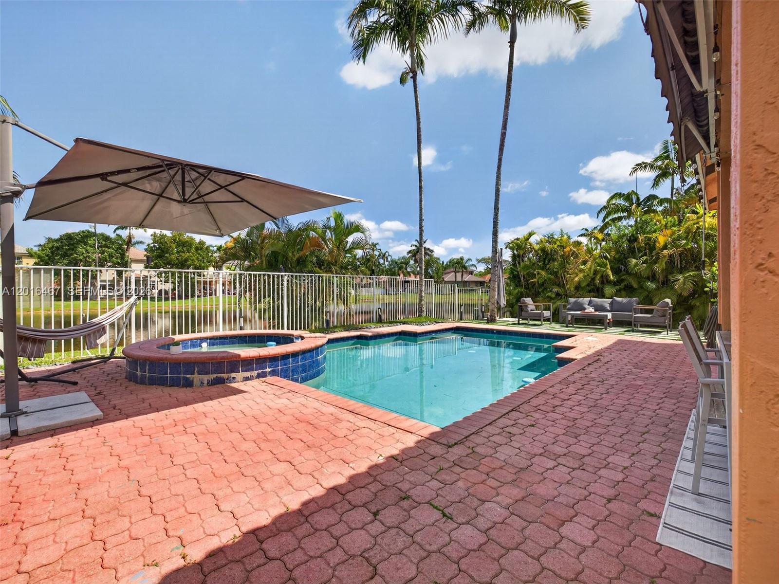 A backyard features a swimming pool, a raised hot tub, a hammock, and patio furniture — 250 Conservation Dr, Weston FL 33327, WESTON, FL