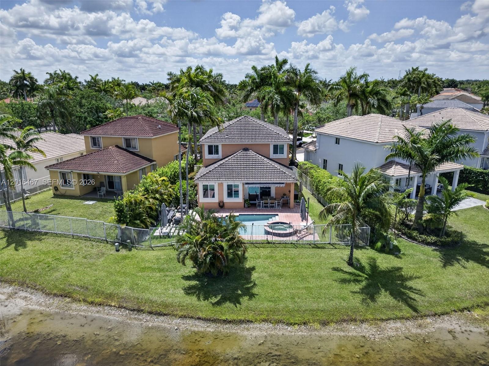 An aerial view shows a two-story house with a pool and patio near a lake — 250 Conservation Dr, Weston FL 33327, WESTON, FL