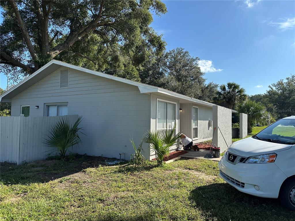 A person paints the exterior of a light gray house with a white car parked nearby — 5435 SE 28TH LANE, OCALA, FL