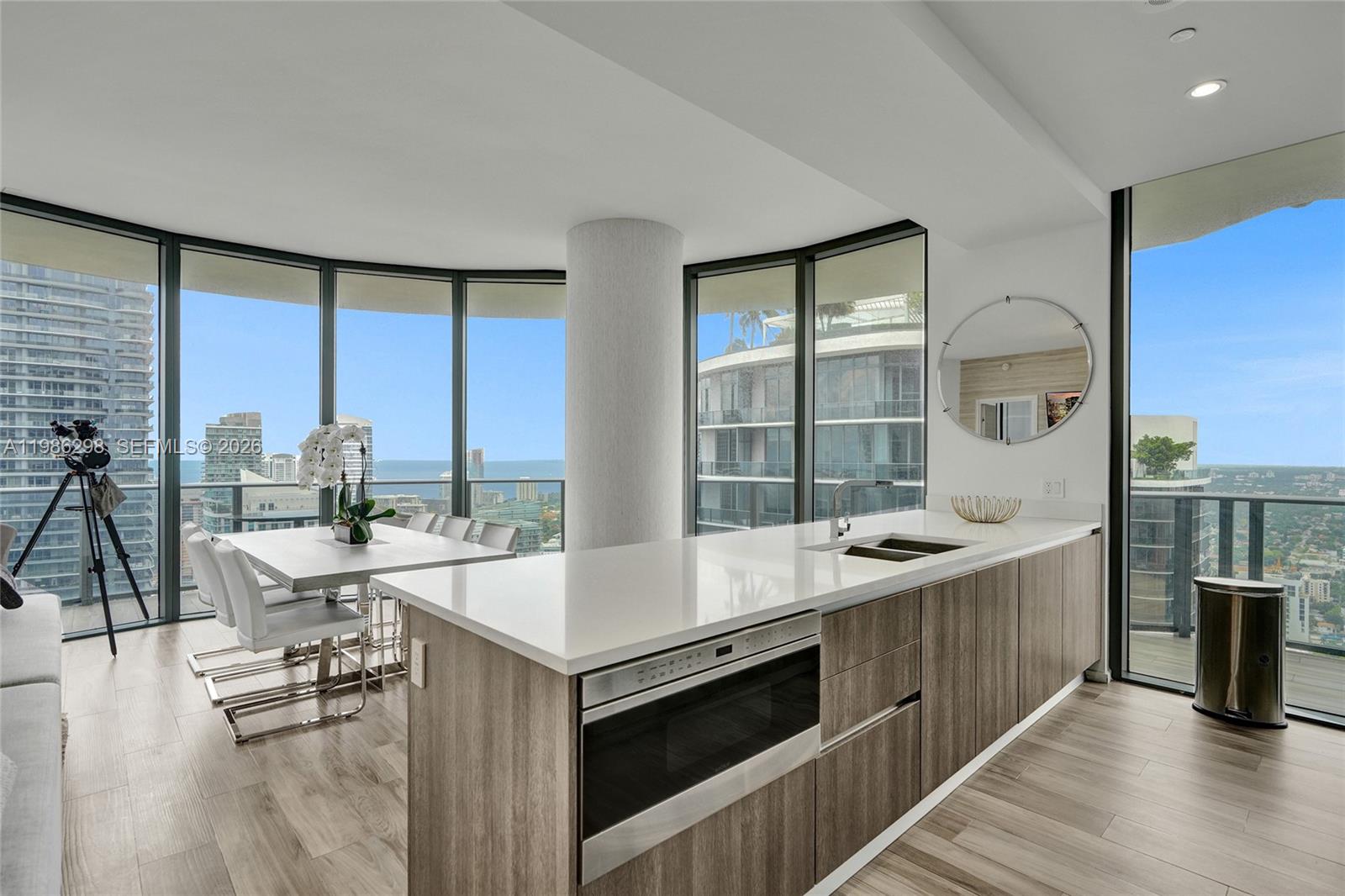 A modern kitchen with wood-toned cabinetry and a white island overlooks a high-rise city view — 801 S Miami Ave # 4901, Miami FL 33130, MIAMI, FL