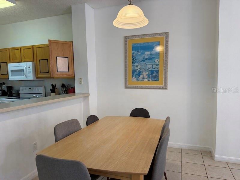 A dining area features a wooden table, grey chairs, a pendant light, and wall art — 4754 VERO BEACH PLACE, KISSIMMEE, FL