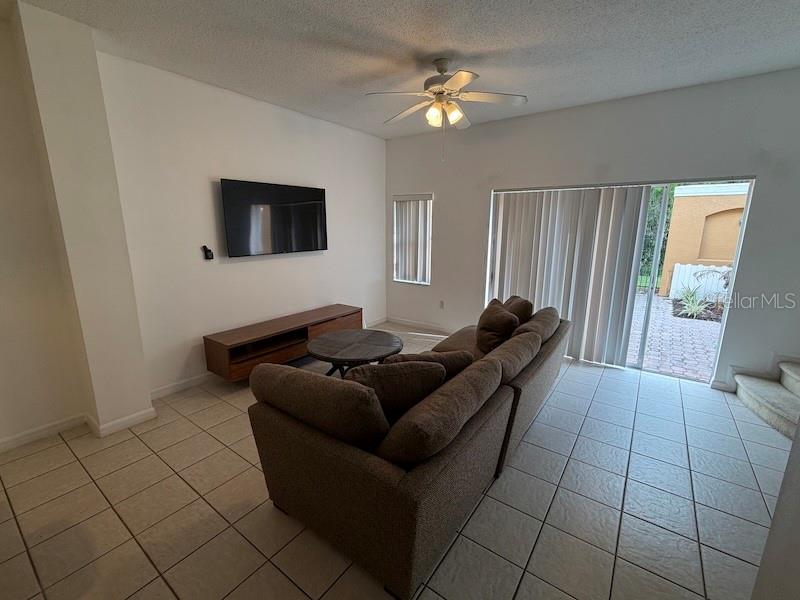 A living room features a brown sofa, a television, a media console, and tile flooring — 4754 VERO BEACH PLACE, KISSIMMEE, FL