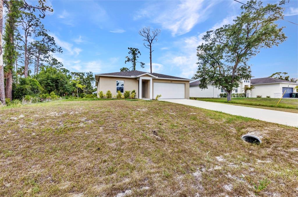 A single-story house with a beige exterior, a two-car garage, and a grassy front yard — 3799 LAREDO AVENUE, NORTH PORT, FL