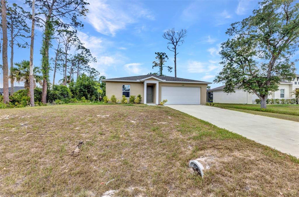 A single-story house with a beige exterior, a two-car garage, and a concrete driveway — 3799 LAREDO AVENUE, NORTH PORT, FL