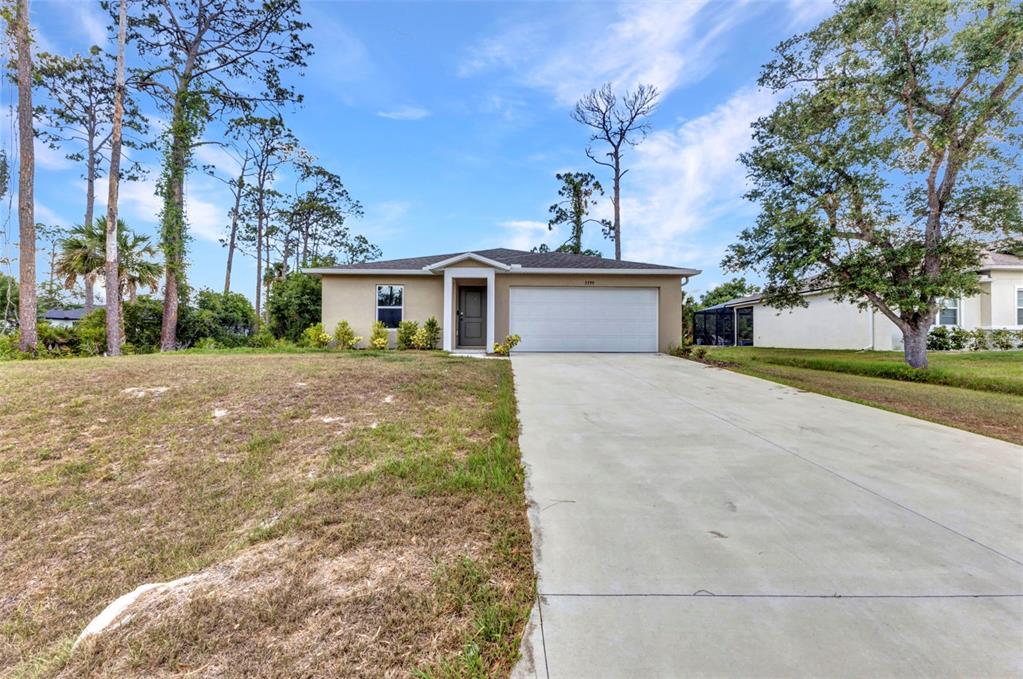 A single-story house with a beige stucco exterior, a two-car garage, and a concrete driveway — 3799 LAREDO AVENUE, NORTH PORT, FL