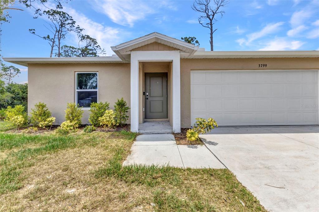A single-story house exterior features a beige stucco facade, a garage, and a front entrance — 3799 LAREDO AVENUE, NORTH PORT, FL