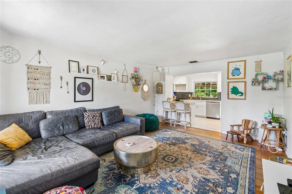 A living room with a gray sectional sofa, patterned rug, and open access to a kitchen — 3742 MARTIN STREET, ORLANDO, FL