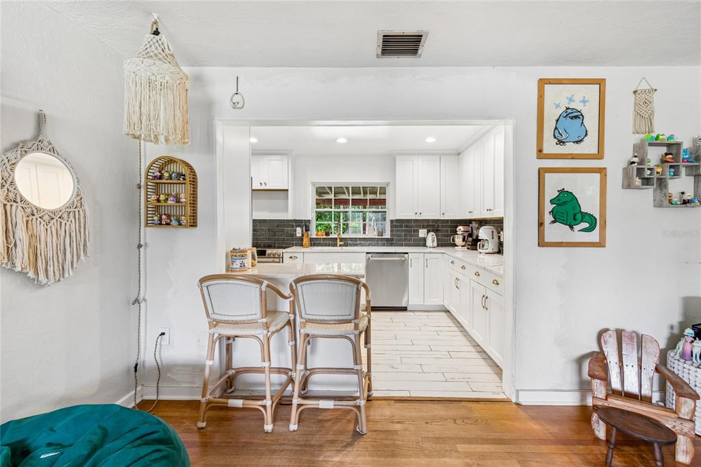 A kitchen with white cabinets and a breakfast bar overlooks a living area — 3742 MARTIN STREET, ORLANDO, FL