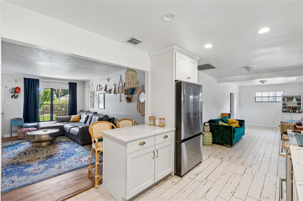 A kitchen island and stainless steel refrigerator separate a living room from a dining area — 3742 MARTIN STREET, ORLANDO, FL