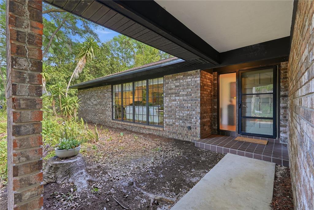 A brick exterior home features a covered entryway, a large window, and a front yard — 3705 NW 25TH AVENUE, GAINESVILLE, FL