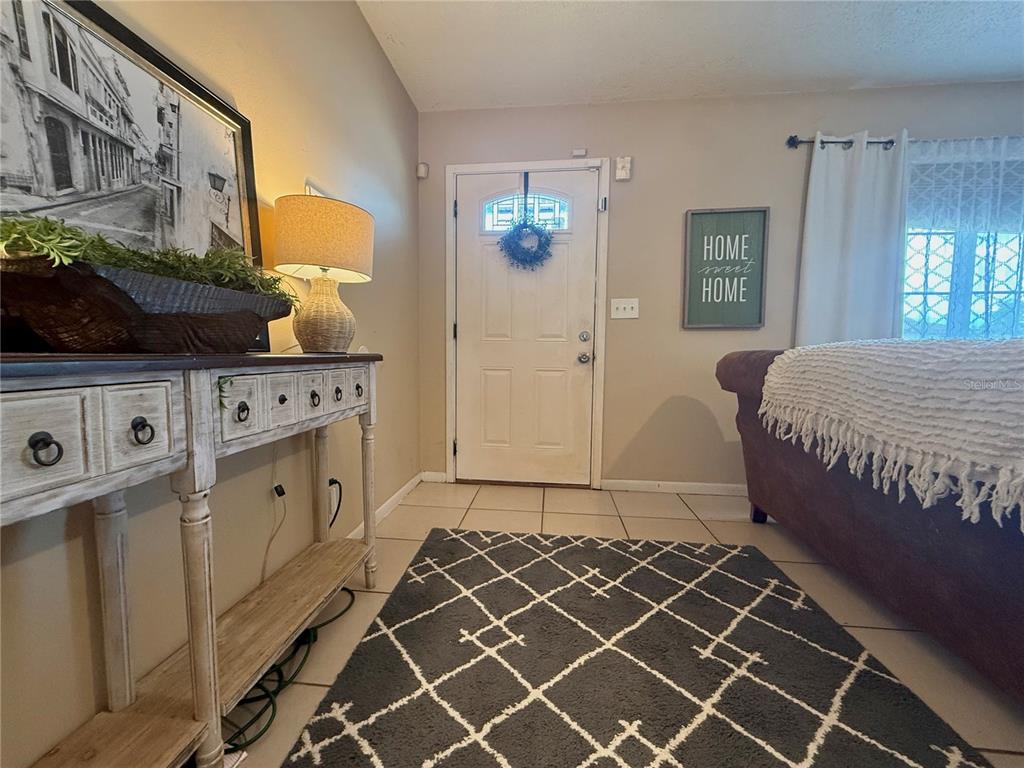 An entryway features a white door, a console table, a patterned rug, and tile flooring — 6 SPRING LANE WAY, OCALA, FL