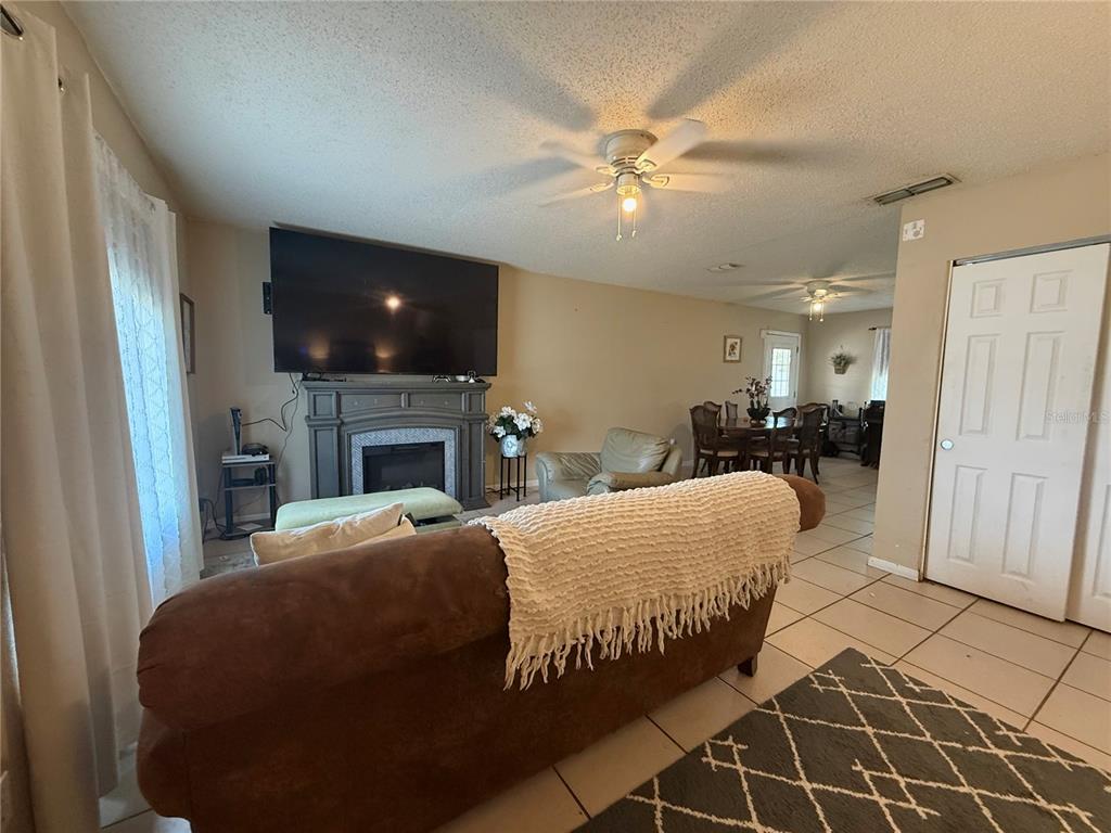 A living room features a fireplace with a mounted television, tile flooring, and dining area — 6 SPRING LANE WAY, OCALA, FL