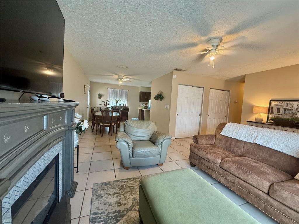 A living room with a fireplace, brown sofa, green armchair, and an adjacent dining area — 6 SPRING LANE WAY, OCALA, FL