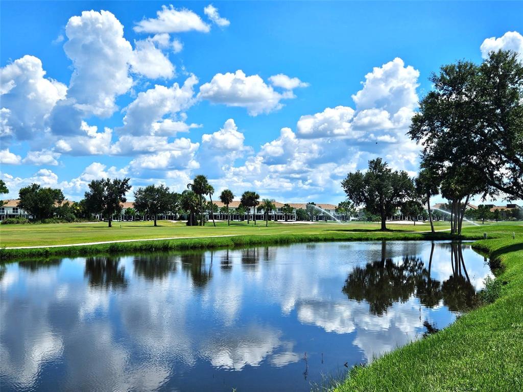 A pond reflects the sky and trees in front of a golf course and buildings — 1394 SAXONY CIRCLE, PUNTA GORDA, FL