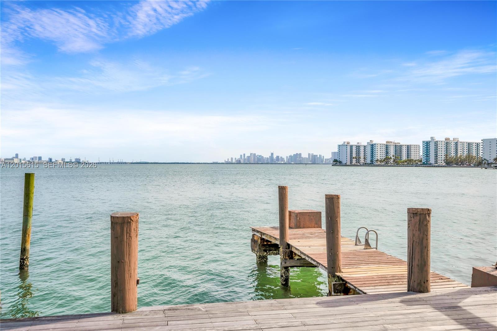 A wooden dock extends into a bay with a distant city skyline in the background — 1920 Bay Dr, Miami Beach FL 33141, MIAMI BEACH, FL