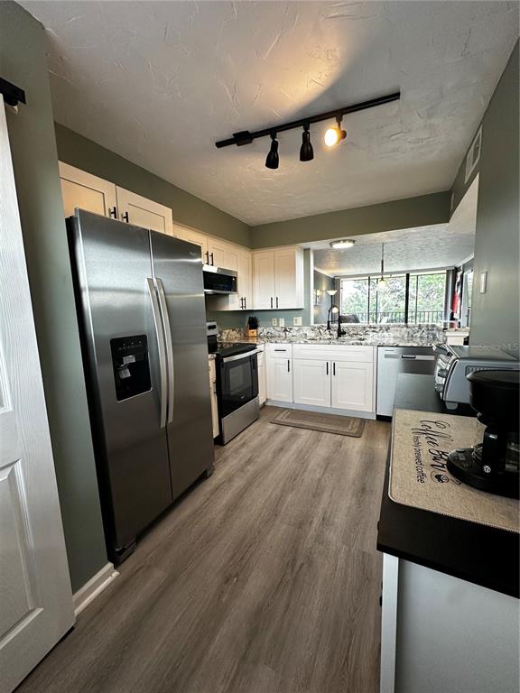 A kitchen features white cabinets, stainless steel appliances, and a sliding barn door — 800 COVE CAY DRIVE UNIT 4F, CLEARWATER, FL