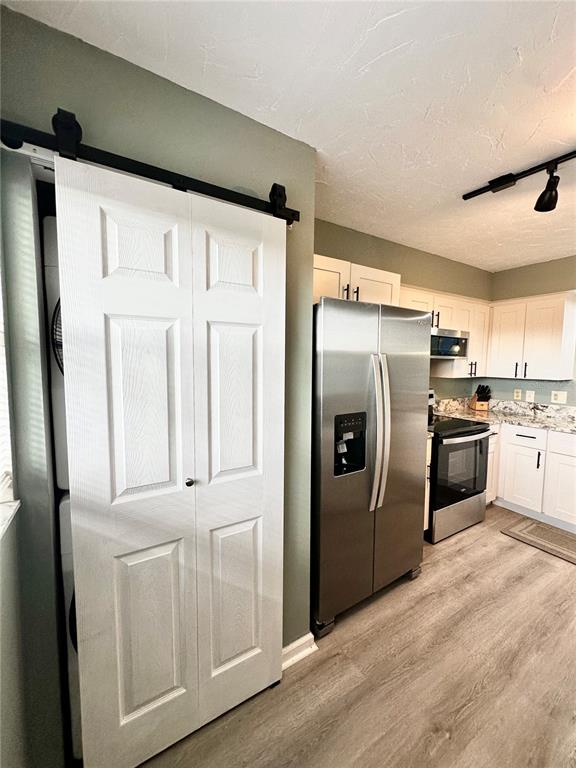 A kitchen features a stacked Whirlpool washer and dryer unit next to a stainless refrigerator — 800 COVE CAY DRIVE UNIT 4F, CLEARWATER, FL