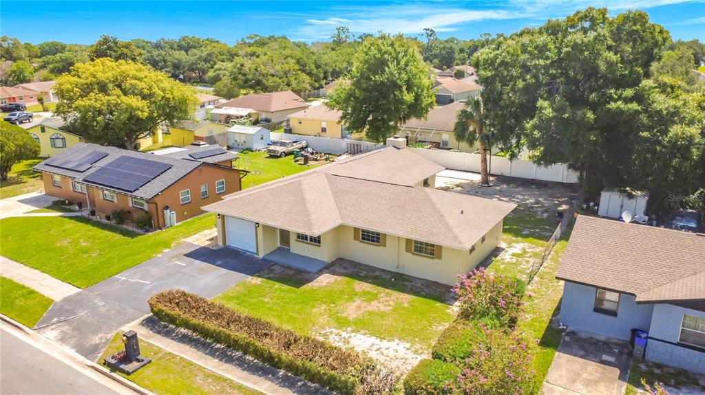 An aerial view shows a tan single-story house with a brown roof and a driveway — 115 DREW AVENUE, SANFORD, FL