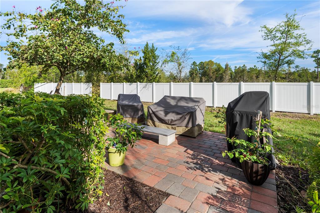 A backyard patio features a brick floor, covered outdoor furniture, and a white vinyl fence — 3719 CROFTON COURT, FORT MYERS, FL