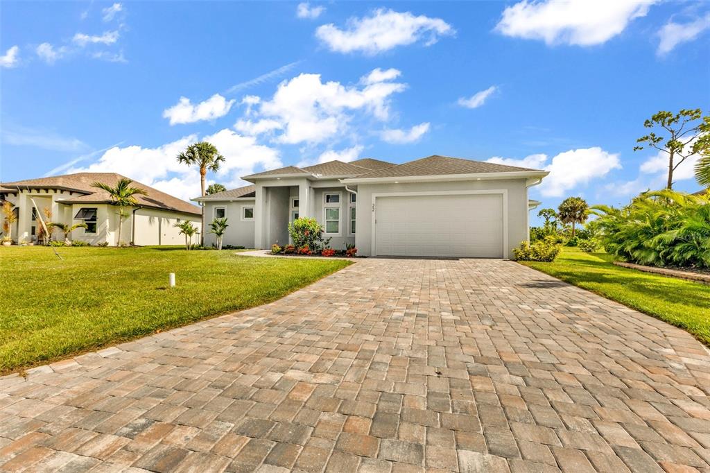 A single-story house with a paved driveway, two-car garage, and a light-colored stucco exterior — 22 SPORTSMAN CIRCLE, ROTONDA WEST, FL