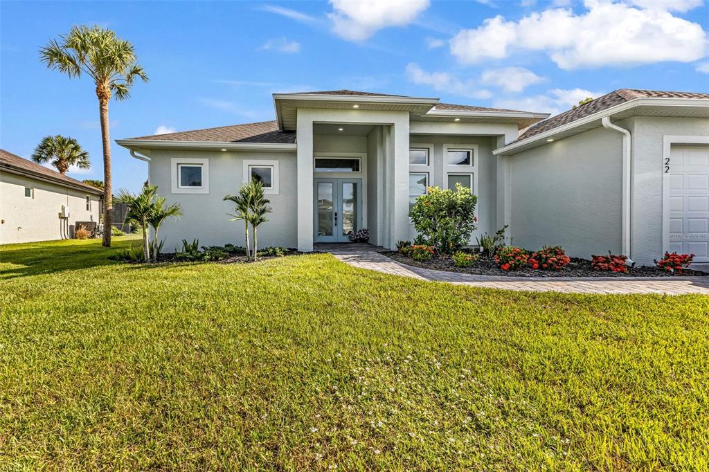 The exterior of a single-story house features a paved walkway leading to double front doors — 22 SPORTSMAN CIRCLE, ROTONDA WEST, FL