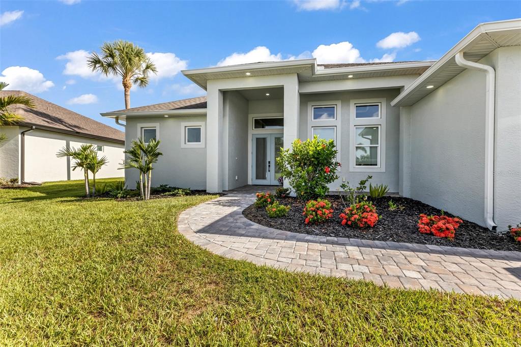 A paved walkway leads to the front entrance of a light-colored single-story suburban home — 22 SPORTSMAN CIRCLE, ROTONDA WEST, FL