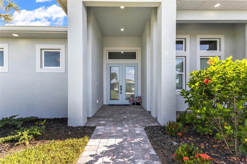 A paved walkway leads to the light blue double front doors of a stucco home — 22 SPORTSMAN CIRCLE, ROTONDA WEST, FL