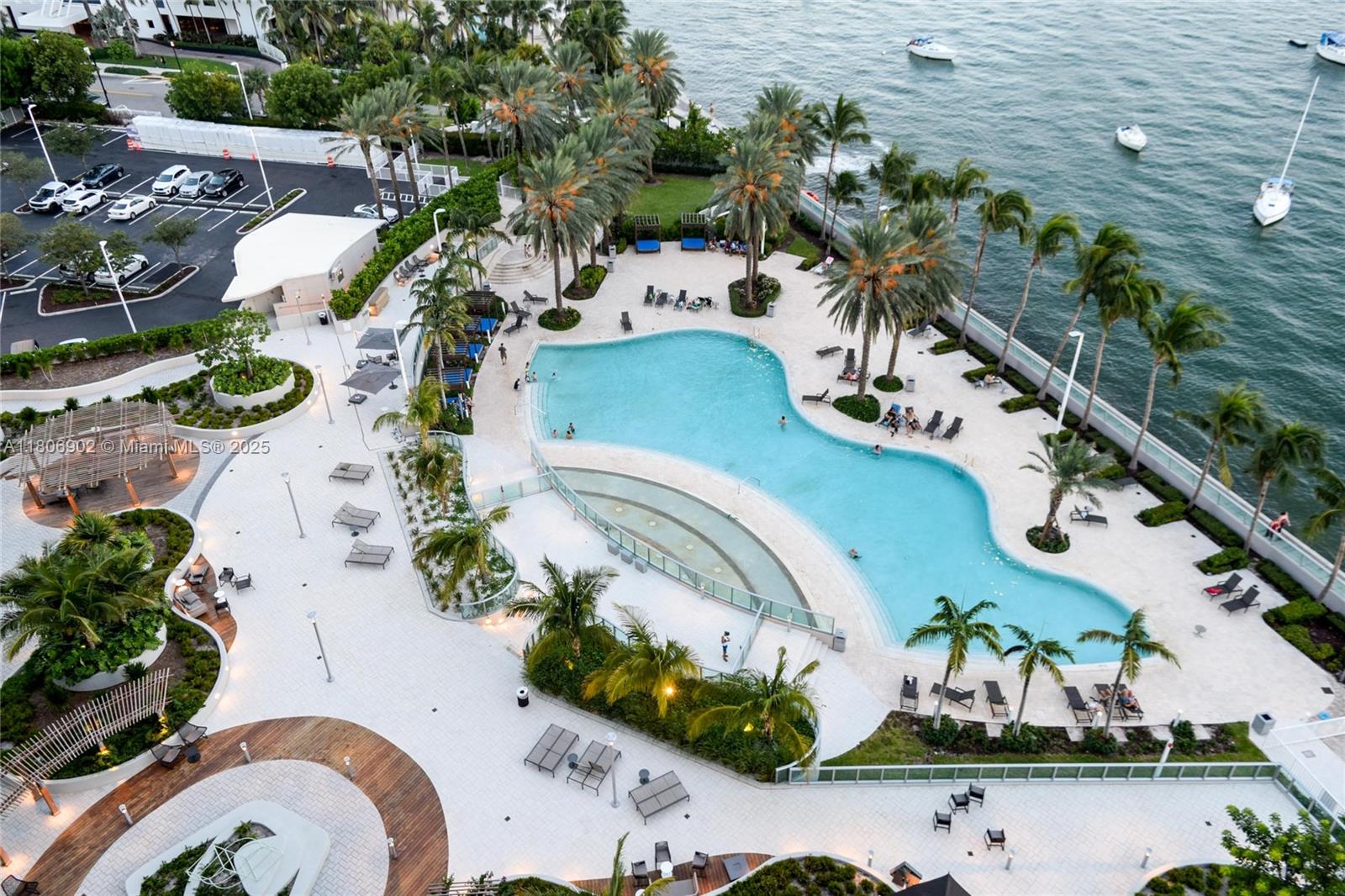 An aerial view shows a swimming pool area with lounge chairs, palm trees, and waterfront access — 1500 Bay Rd # 1532S, Miami Beach FL 33139, MIAMI BEACH, FL