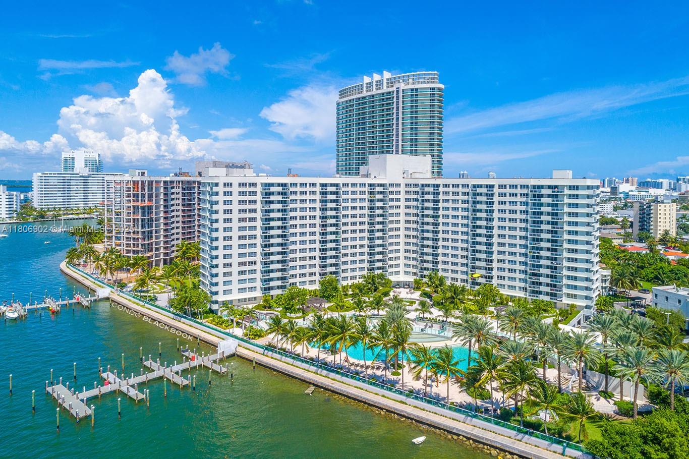 An aerial view shows a large white apartment building with a pool and boat dock — 1500 Bay Rd # 1532S, Miami Beach FL 33139, MIAMI BEACH, FL