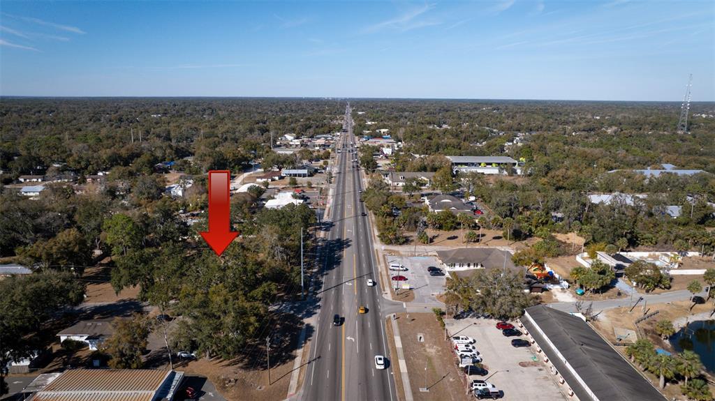 An aerial view shows a wooded lot marked by a red arrow beside a highway — S VOLUSIA AVENUE, ORANGE CITY, FL