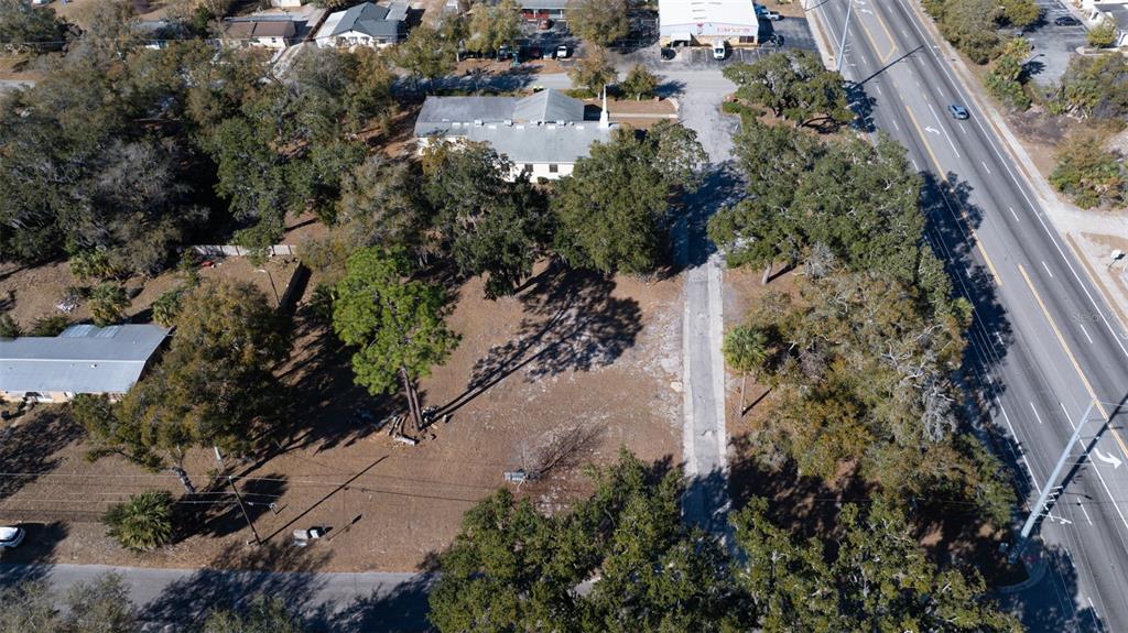 An aerial view shows a vacant lot with trees situated between a road and buildings — S VOLUSIA AVENUE, ORANGE CITY, FL