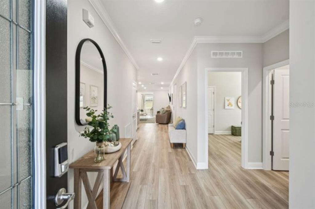 A bright entryway features light wood-look flooring, a console table, and a tall arched mirror — 39 PORT ROYAL DRIVE, PALM COAST, FL