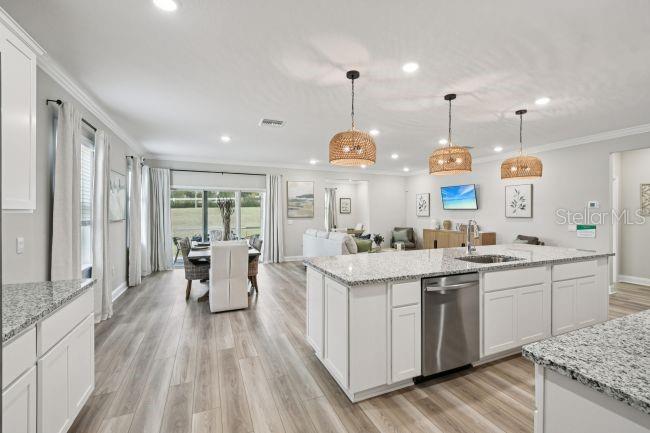 A bright, open-concept kitchen and dining area features white cabinetry, granite countertops, and wood flooring — 39 PORT ROYAL DRIVE, PALM COAST, FL