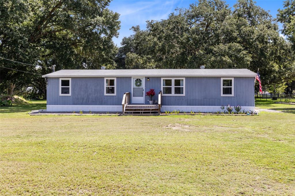 A living room with gray carpet, a television on a wooden stand, and a recliner — 5136 SHEPARD LANE, POLK CITY, FL