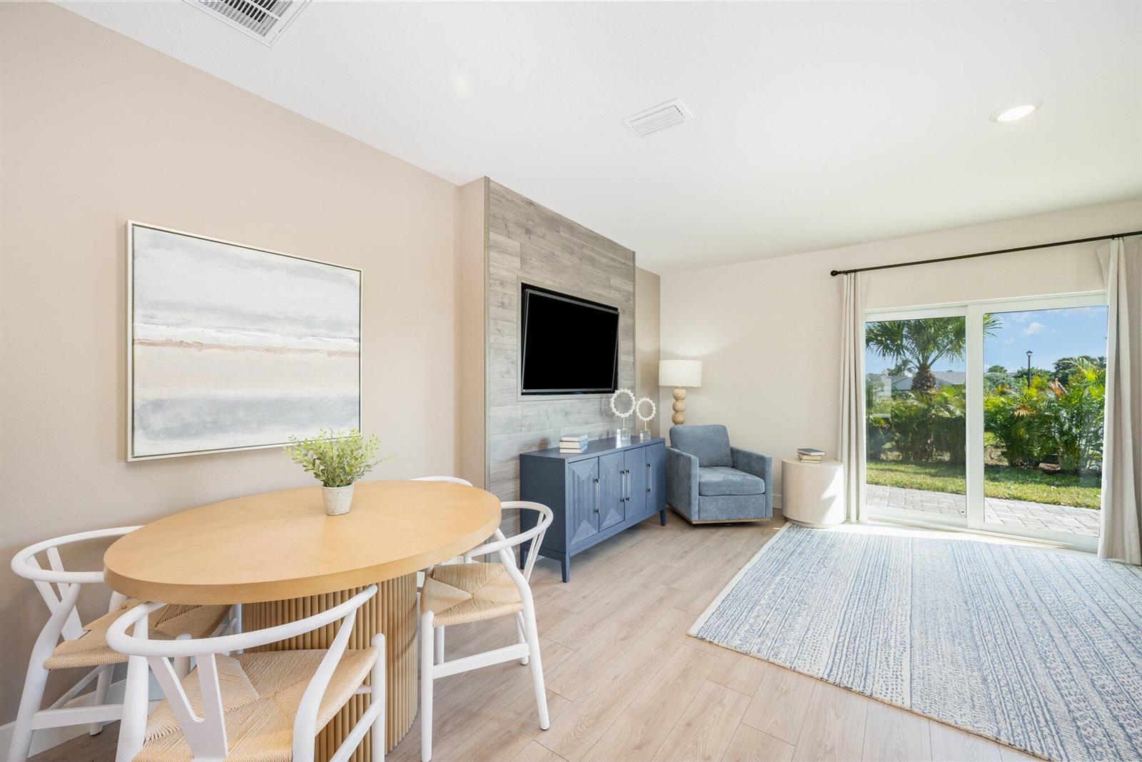 A dining area and living space feature wood-look flooring, a blue cabinet, and sliding doors — 8136 Cobblestone Drive, Fort Pierce FL 34945, FORT PIERCE, FL
