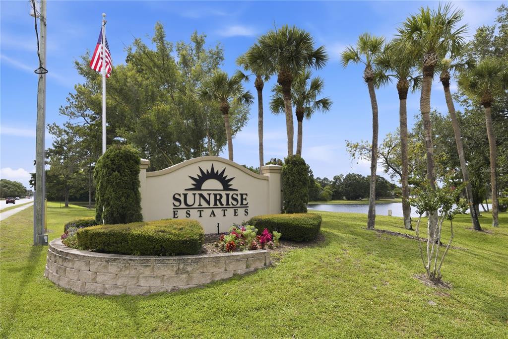 A beige monument sign for Sunrise Estates stands in a grassy area with palm trees — 1389 PONCE DE LEON BOULEVARD, WINTER SPRINGS, FL