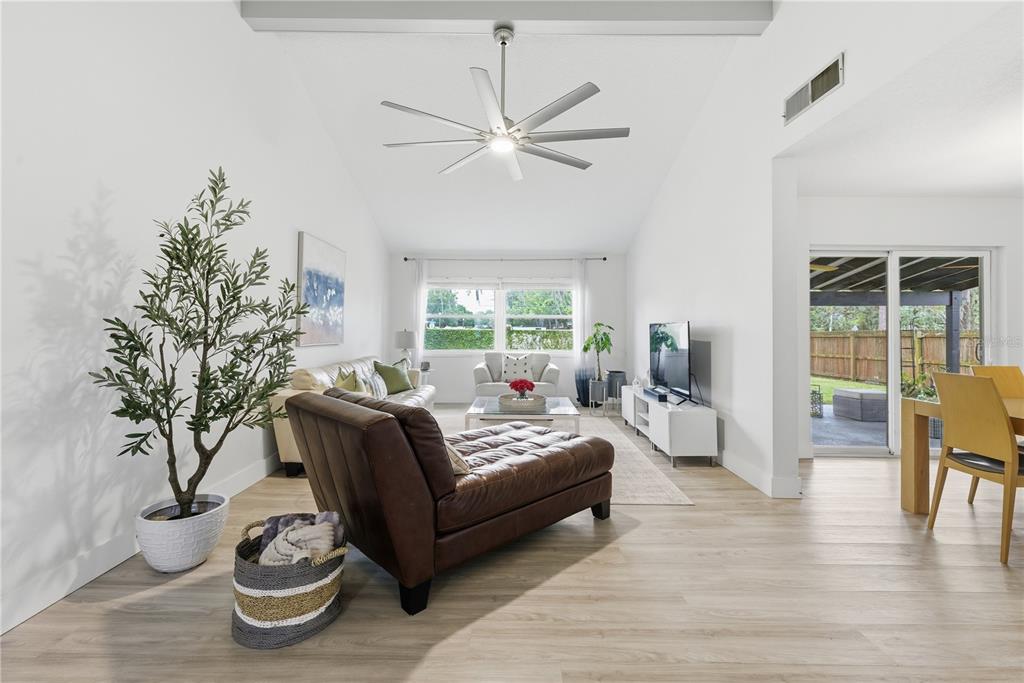 A bright living room features light wood-look flooring, a vaulted ceiling, and a sliding glass door — 1389 PONCE DE LEON BOULEVARD, WINTER SPRINGS, FL