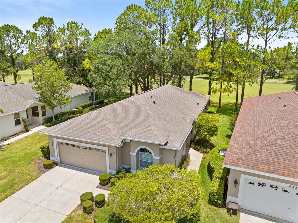 An aerial view shows two suburban houses with beige stucco walls and brown shingled roofs — 14425 STERLING RUN, SPRING HILL, FL