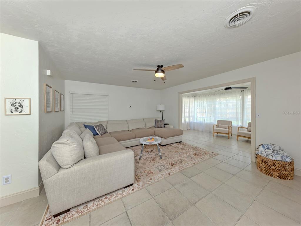 A living room features a large sectional sofa, a patterned area rug, and tile flooring — 929 CYPRESS AVENUE, VENICE, FL