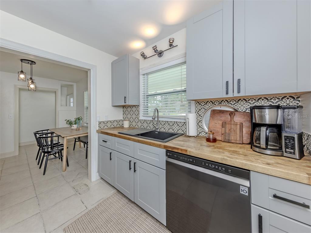 A kitchen features gray cabinets, a wood countertop, a black sink, and patterned tile backsplash — 929 CYPRESS AVENUE, VENICE, FL