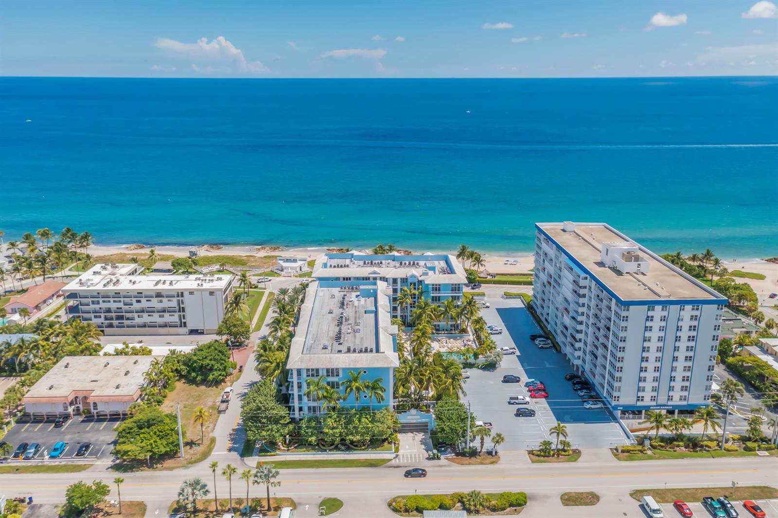 An aerial view shows three multi-story apartment buildings situated along a sandy beach and ocean — 701 SE 21st Avenue # 204, Deerfield Beach FL 33441, DEERFIELD BEACH, FL