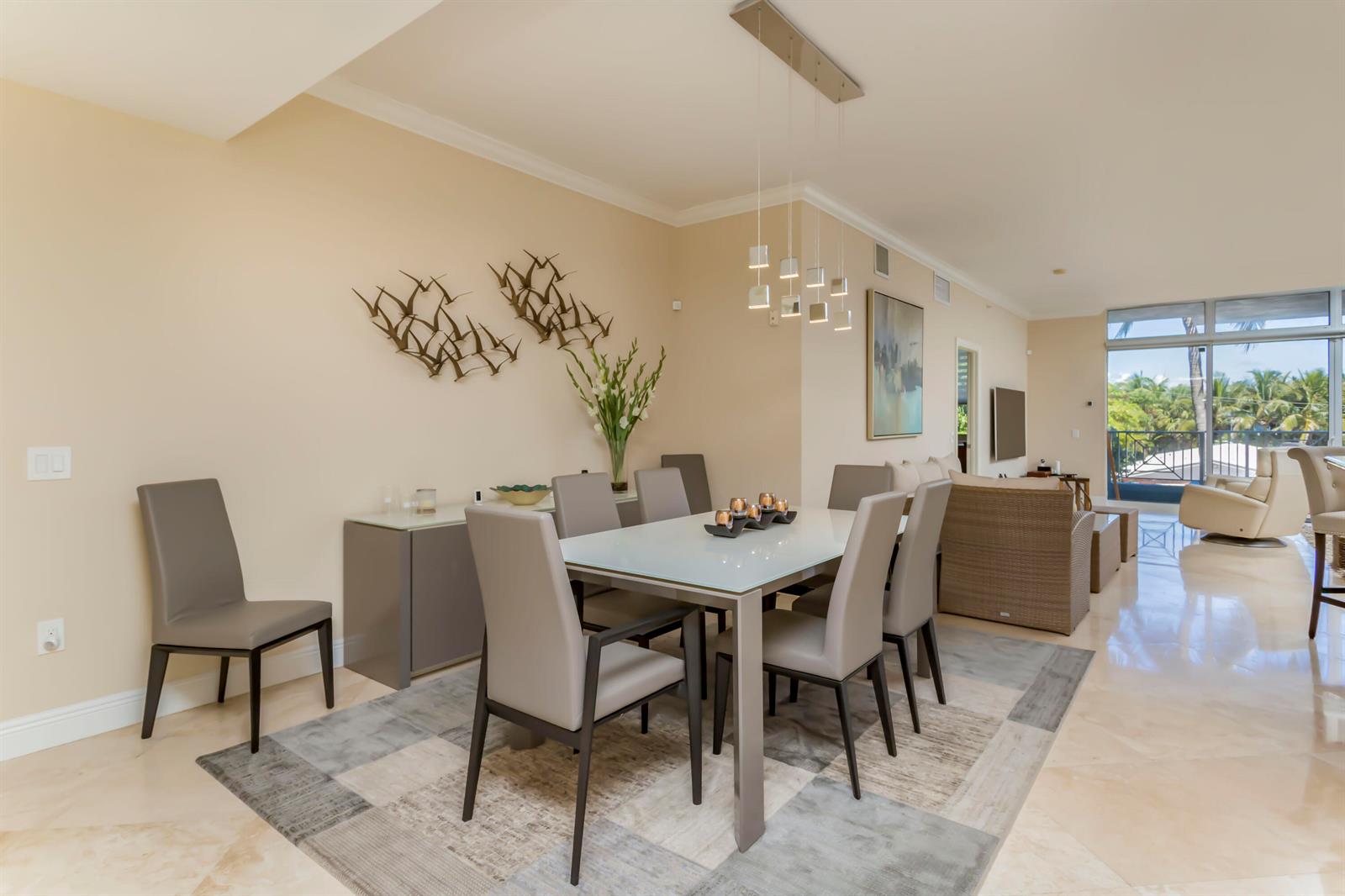 A dining area with a glass-topped table, grey chairs, and a modern light fixture — 701 SE 21st Avenue # 204, Deerfield Beach FL 33441, DEERFIELD BEACH, FL