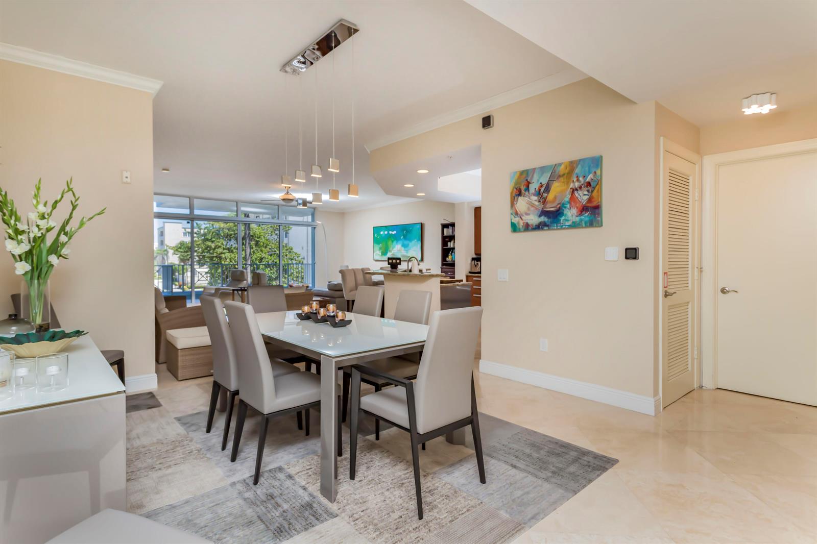 A dining area with a glass-top table and six chairs sits before an open living space — 701 SE 21st Avenue # 204, Deerfield Beach FL 33441, DEERFIELD BEACH, FL