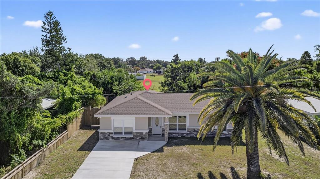 An exterior view of a single-story house with a palm tree and concrete driveway — 5352 TANGERINE DRIVE, NEW PORT RICHEY, FL