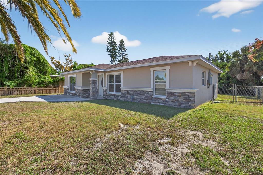 A single-story house with tan stucco walls, stone veneer accents, and a brown shingled roof — 5352 TANGERINE DRIVE, NEW PORT RICHEY, FL