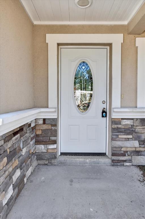 A white front door with an oval glass insert sits between stone-clad exterior walls — 5352 TANGERINE DRIVE, NEW PORT RICHEY, FL