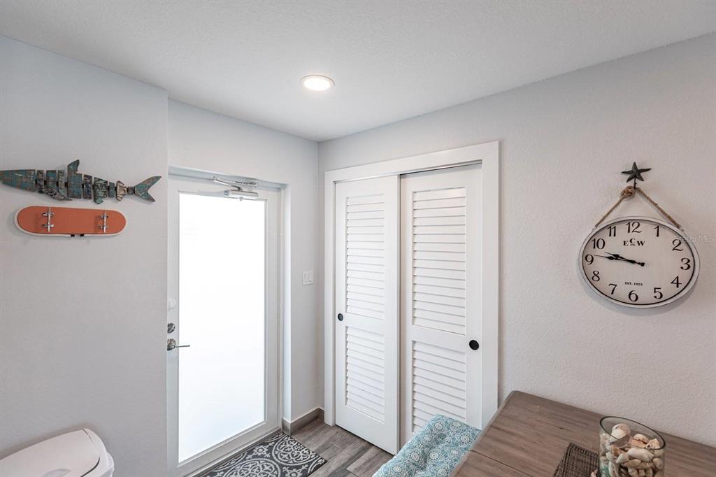A room features a glass door, louvered closet doors, a wall clock, and a fish decoration — 6154 MIDNIGHT PASS ROAD UNIT 202, SARASOTA, FL