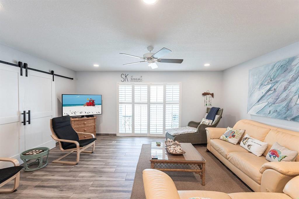 A living room features a beige sofa, two armchairs, a coffee table, and sliding barn doors — 6154 MIDNIGHT PASS ROAD UNIT 202, SARASOTA, FL
